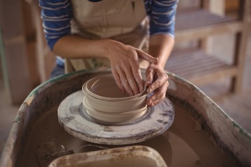 Mid section of female potter making pot
