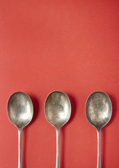 Silver serving spoons on a red background forming a page border