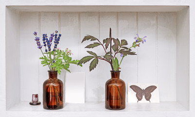 Fototapeta premium Shelf with lavender and geranium in old pharmacy bottles.