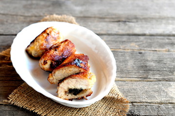 Meat rolls on a plate and on old wooden table with copy space for text. Roasted Turkey breast stuffed with cheese and mushrooms. Tasty meat recipe. Closeup