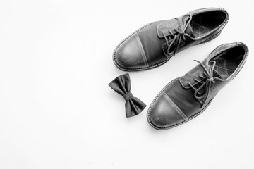 Men's accessories outfits with leather shoes and bow tie, top view, flat lay on wooden board background, black and white