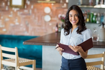 Smiling mixed race waitress holding a file