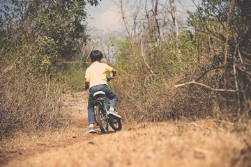 Little boy ride bicycle on the rock road.