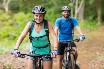 Athletic couple cycling in forest