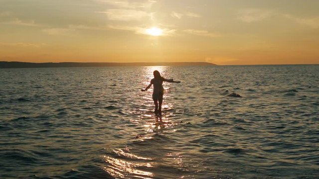 girl dancing in the sea in the sunset