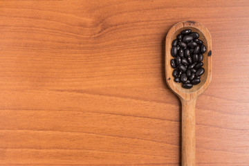 Black beans into a spoon over a wooden table