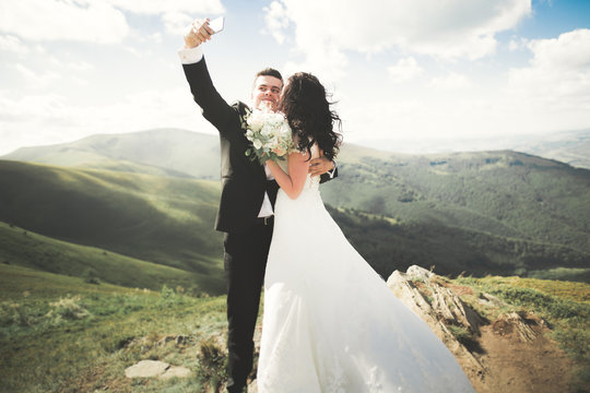 Just married couple on top of the mountain taking selfie picture
