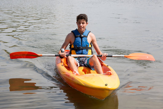 Happy young man rowing on lake in kayak and smiling