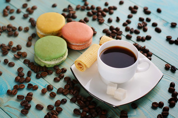 Coffee cup with wafer and macaroons on blue wood background