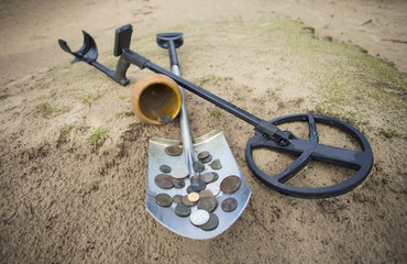 Pot of gold coins collected with help of metal detector, green grass background.