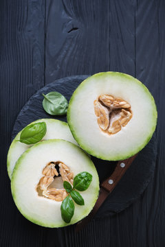 Above view of sliced juicy melon on a black wooden background