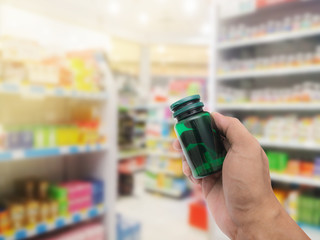 Hand with plastic pill bottle on pharmacy store
