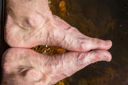 Close up of rough feet with veins, reflection in water outdoors. 