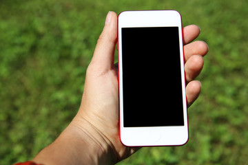 Hand holding smartphone against green background