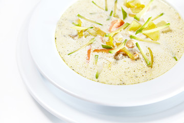 White soup with vegetables on white background