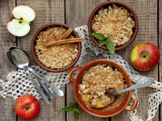 Cheese casserole or crumble with apples and cinnamon in brown cup ramekin on wooden background