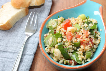 Eine Portion frischer CousCous-Salat in einer kleinen Schüssel mit Brot, Kuskus mit Zwiebeln und Tomaten