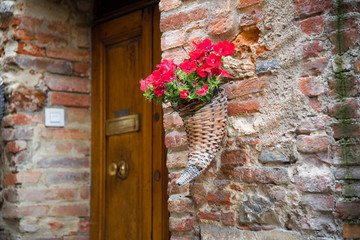 Cornucopia with flowers, somewhere in the medieval town Lucignano in Tuscany, Italy.