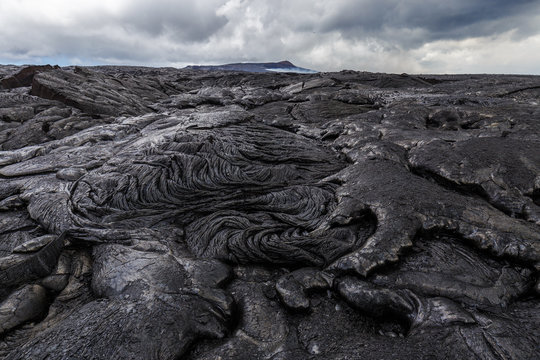 Bizarre formations on the lava fields of Puu Oo, Big Island Hawaii. The shiny rock consists of very fresh lava. The cone of Puu Oo is visible in the background.