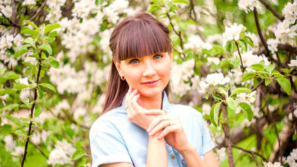 Portrait of pretty young brunette posing in flowering trees