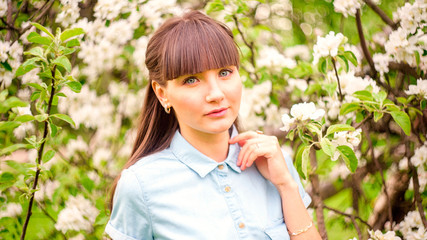 Portrait of pretty young brunette posing in flowering trees