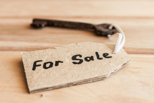 The concept of sale of property - old key, inscribed on label on wooden background.