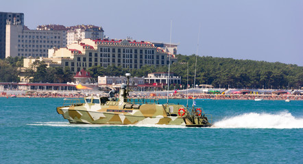 Obraz premium military boat at full speed makes blank volley of guns on the city beach. Russia, Gelendzhik