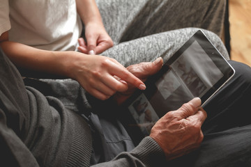 Daughter helps his father to use the tablet. Taught to use the internet while sitting on a sofa. mock up