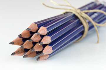 Matite blu legate con spago su superficie bianca © errem