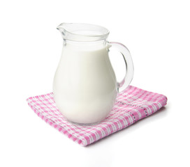 Milk in a glass jug on pink tablecloth isolated