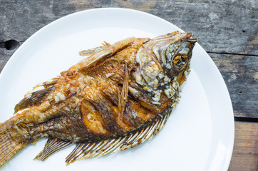 fried fish Tilapia on white dish on wooden background,thai food style