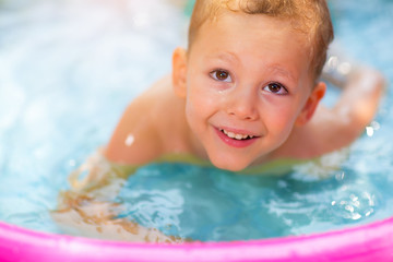 Fototapeta na wymiar Little boy in inflatable swimming pool outdoor, having fun