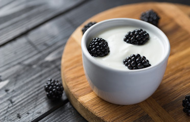 Blackberries in white yogurt on natural cutting boards and woode