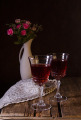 Bouquet of pink roses with two glasses of wine on wooden rustic background. Valentine's Day.