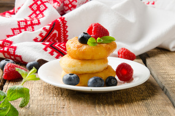 Russian cottage cheese pancakes with raspberries on wooden background. Selective focus.
