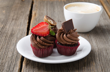 Chocolate cupcakes with strawberry and chocolate on a wooden table.
