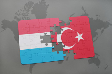 puzzle with the national flag of luxembourg and turkey on a world map background.
