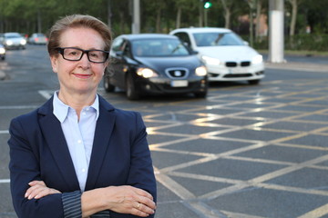 Blond senior business woman in city traffic