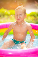 Fototapeta na wymiar Little boy in inflatable swimming pool outdoor, having fun