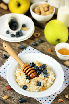 Oatmeal with blueberries, peanuts, honey on the wooden table