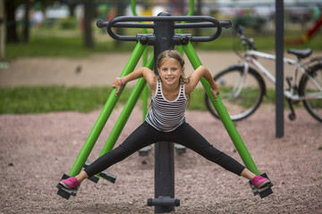 Little cute girl doing stretching on the Playground.