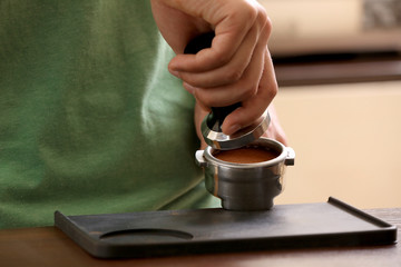 Barista pressing ground coffee with tamper in portafilter