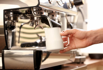 Fototapeta na wymiar Barista whipping milk in coffee machine