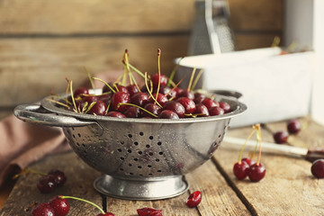 Cherries in colander on wooden table