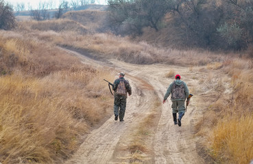 Fototapeta na wymiar Hunters walking with shotguns along the road