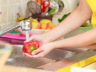 woman washing fresh vegetables in kitchen
