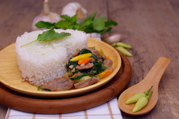 Stir fried spicy basil pork with white rice on wooden table, Thai food.