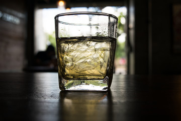 a cup of ice tea on wooden table,dark light style