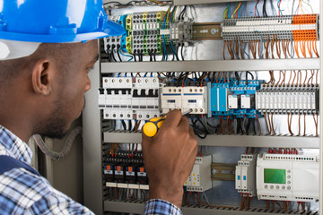 Electrician Examining Fusebox With Screwdriver