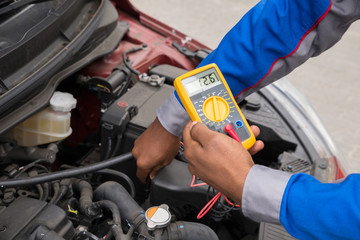 Mechanic Checking Battery With Multimeter